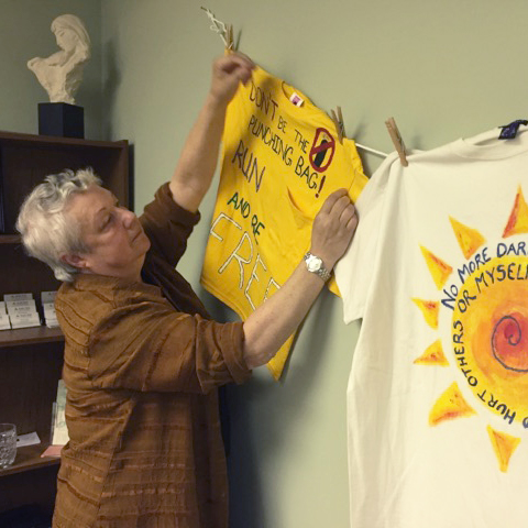 Sarah Ellis hangs inspirational t-shirts in her office at the Shelter for Help in Emergency