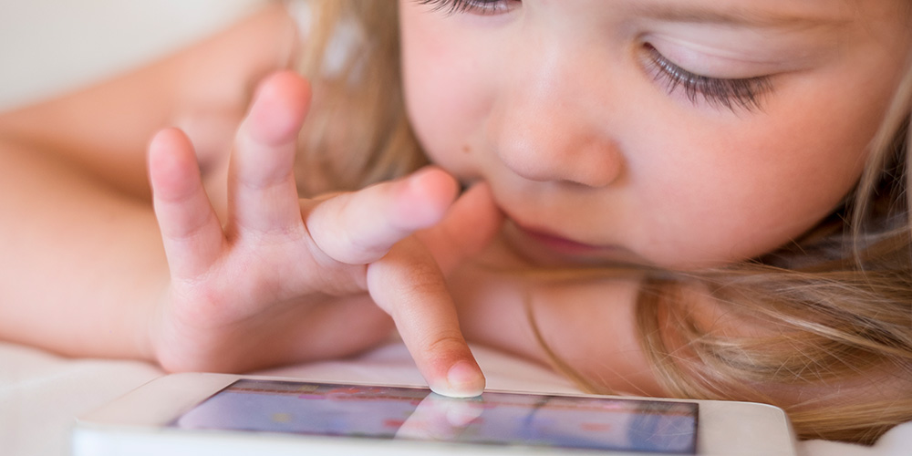 Smartphones. Child using a smartphone in bed