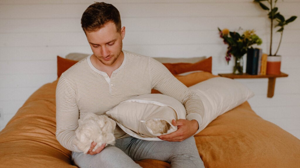 Man reading in bed with an organic body pillow