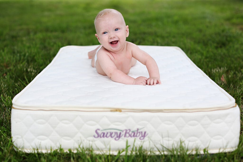 Baby lying on a Savvy Baby organic crib mattress