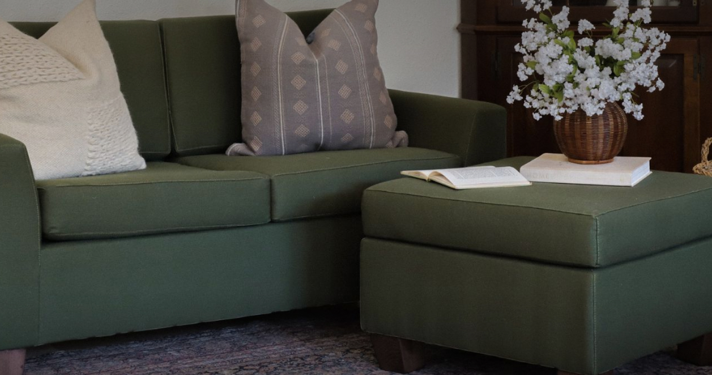 A green Verona organic sofa and matching ottoman in a sunlit living room