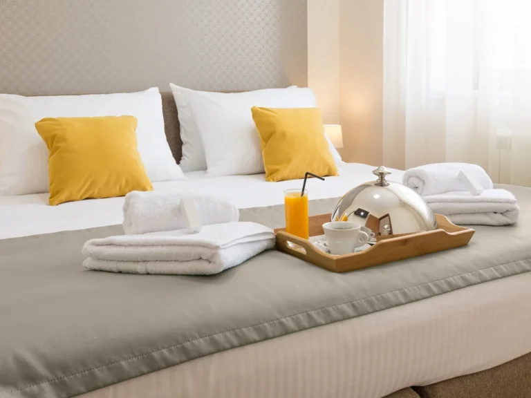 Hotel bed with fresh towels and a breakfast tray